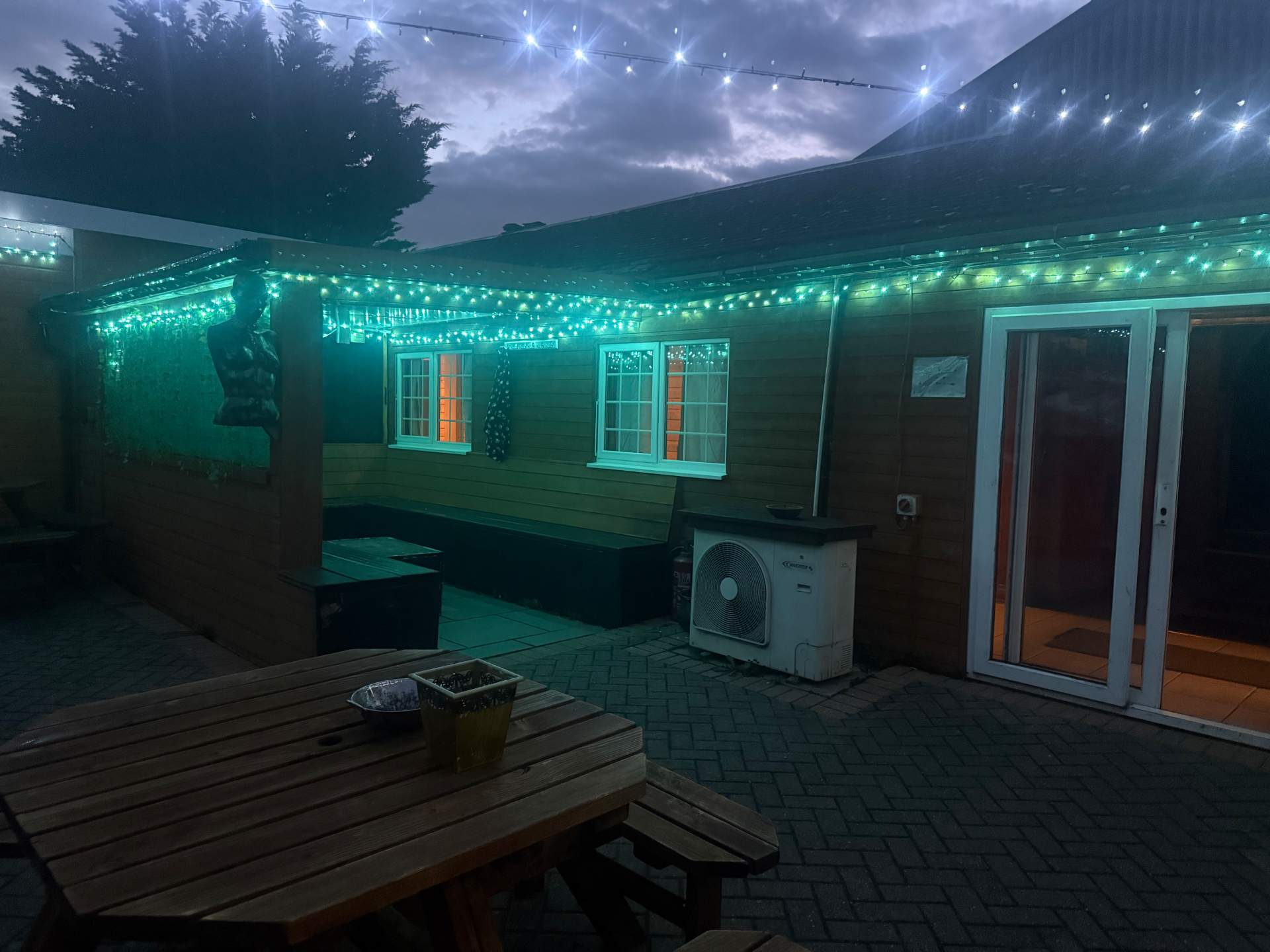 Garden terrace at night lit by green fairy lights